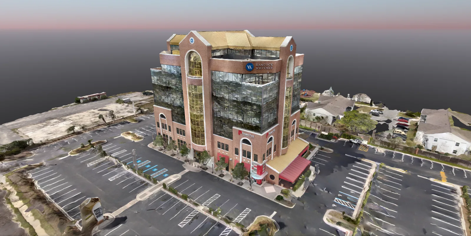 A reconstructed commercial building is shown with its parking area and surroundings.