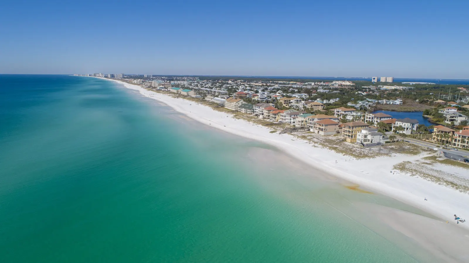 White sand beaches, turquoise water, and coastal homes viewed from the air